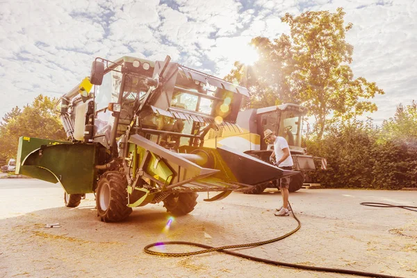 農場の庭で黄色と緑のコンバイン ハーベスターを修理する整備士 — ストック写真