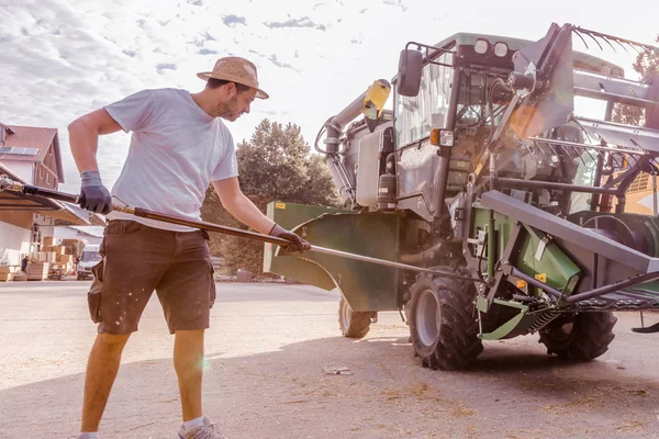 mechanic repairing the yellow and green combine harvester in the farm yard.