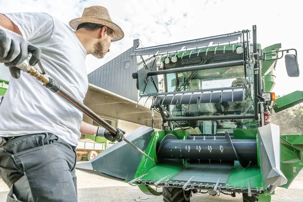 mechanic repairing the yellow and green combine harvester in the farm yard.