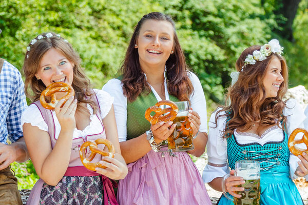 happy friends in Bavarian costumes having fun together outdoors