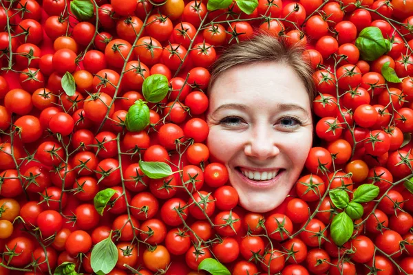 Woman with tomatoes, concept for food industry. Face of emotional woman in tomato surface