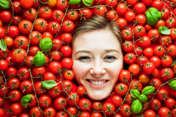 Woman with tomatoes, concept for food industry. Face of emotional woman in tomato surface