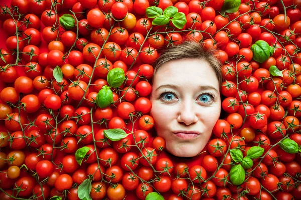 Woman with tomatoes, concept for food industry. Face of emotional woman in tomato surface