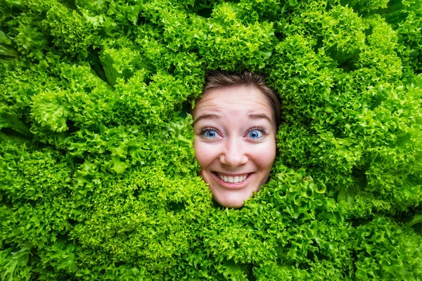 Woman with salad leaves, concept for food industry. Face of laughing woman in salad area.