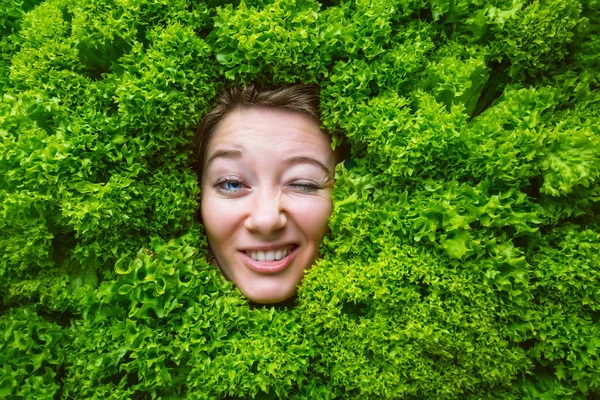 Woman with salad leaves, concept for food industry. Face of laughing woman in salad area.