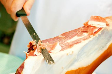 Bıçak tutan ve et kesen birinin kırpılmış görüntüsü.