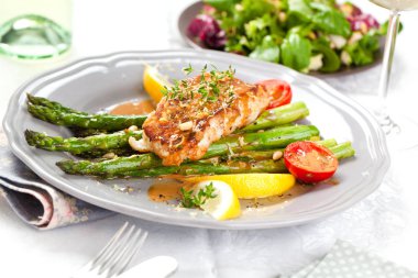 kuşkonmaz, domates, limon ve soslu gurme ızgara somon bifteğinin yakın çekim görünümü  