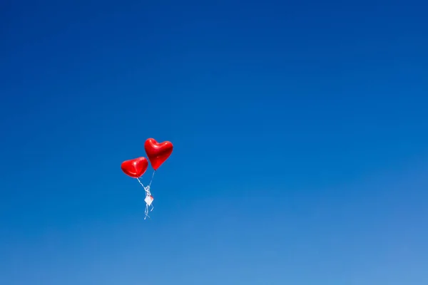 red heart shaped balloons flying in the sky