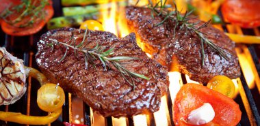 close-up view of delicious steaks with rosemary and vegetables cooking on grill clipart