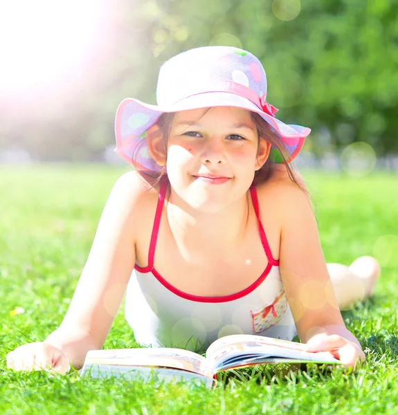 Urocze Dziecko Leżącego Trawie Książki Uśmiechnięty Aparacie — Zdjęcie stockowe