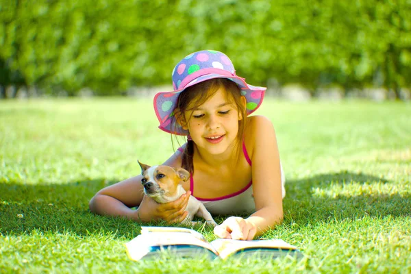 可爱的微笑的孩子躺在草地上与狗和阅读书 — 图库照片#