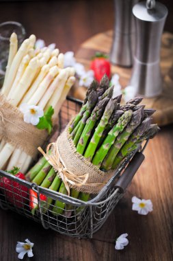 taze yeşil ve beyaz kuşkonmaz, çiçek ve ahşap masa üzerinde olgun çilek sepeti