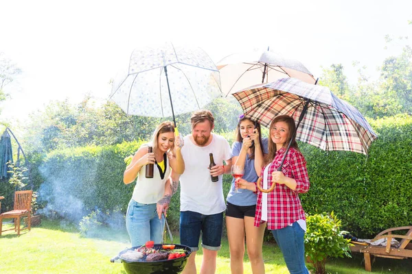 友達屋外でぶら下がったり 傘を持ったり 裏庭でバーベキューをしたり — ストック写真
