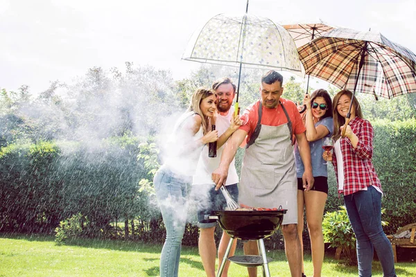 Freunde Hängen Draußen Halten Regenschirme Der Hand Und Grillen Garten — Stockfoto