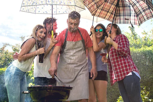 朋友们一起出去玩 在后院拿着雨伞 做着烧烤 — 图库照片