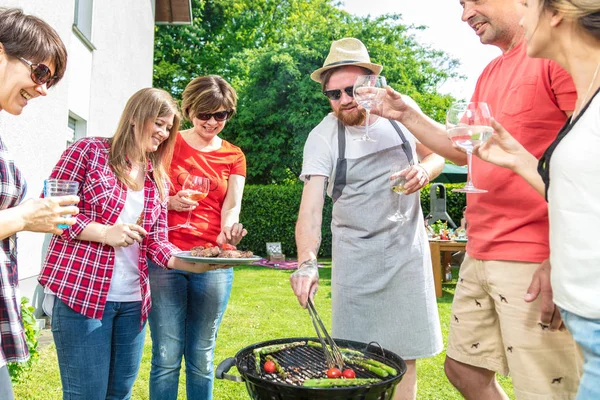 裏庭で過ごす多様な人々の友人 肉を焼くとアルコール飲料を飲む — ストック写真