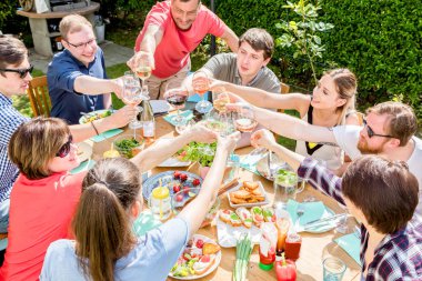 Bir grup arkadaş açık hava barbeküsü yapıyorlar. Alkollü şarap içiyorlar.