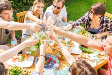 Bir grup arkadaş açık hava barbeküsü yapıyorlar. Alkollü şarap içiyorlar.