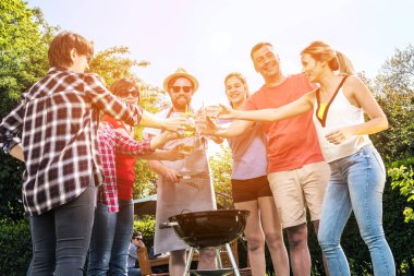 Çeşitli İnsanlar Arka bahçede takılıyor, Bira içiyor ve Barbekü pişiriyor.