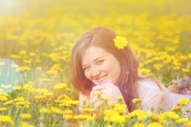 Dandelions çayır, gevşeme ilkbaharda, tatil açık üzerinde mutlu neşeli kız Dandelions sahada uzanmış güzel kadın
