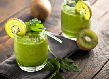 ahşap masa üzerinde yeşil ev yapımı kivi smoothies ile gözlük
