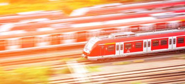 Renkli günbatımında hareket bulanıklığı olan modern yüksek hızlı kırmızı banliyö treni