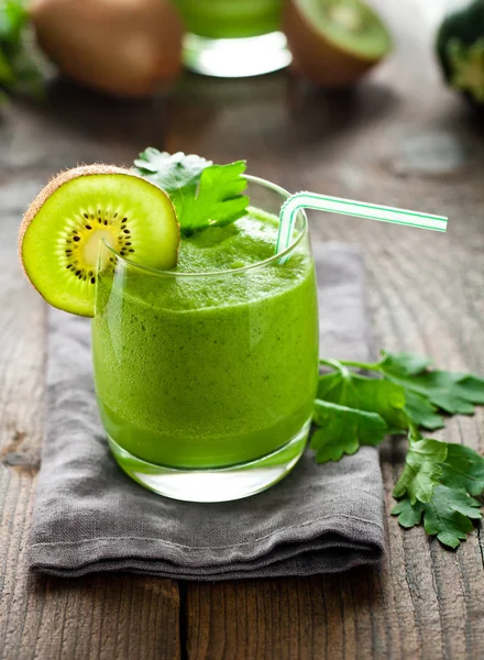 kivi smoothie, maydanoz ve ahşap masa üzerinde saman içme ile cam yakın çekim görünümü
