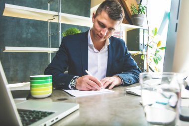 yakışıklı odaklı genç işadamı ofiste kağıtları ile çalışan