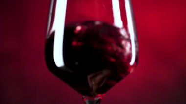 koyu kırmızı arka plan üzerinde cam sallayarak kırmızı şarap yakın çekim görünümü