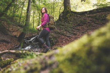 ormanda yürüyüş gülümseyen genç kadın backpacker düşük açı görünümü 