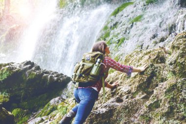 şelale yakınındaki kayaüzerinde tırmanma sırt çantası ile genç kadının arka görünümü