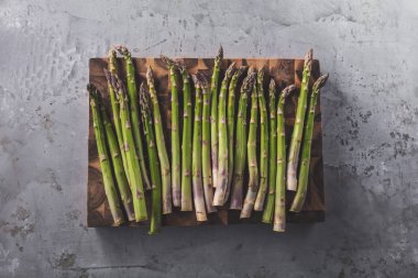 gri yüzeyüzerinde ahşap tahta üzerinde taze ham organik kuşkonmaz üst görünümü