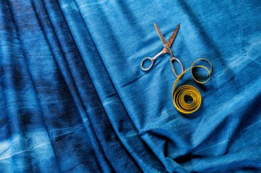 denim kumaş üzerinde sarı ölçüm bandı ve makas üst görünümü, dikiş arka plan  