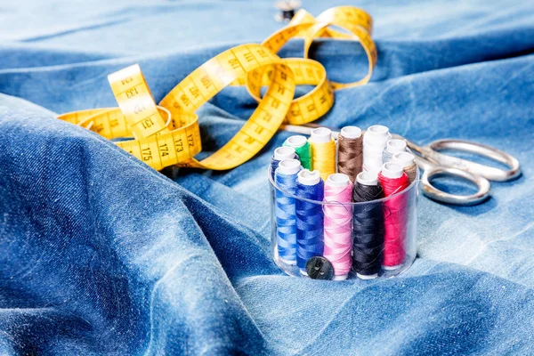 denim kumaş üzerinde ölçüm bandı, makas ve dikiş ipliklerinin yakın çekim görünümü    