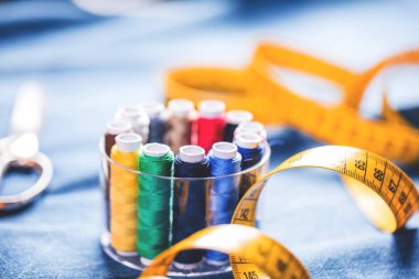 mavi kumaş üzerinde dikiş ve ölçüm bandı için renkli dikiş ipliklerinin yakın çekim görünümü