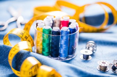 mavi kumaş üzerinde dikiş ve ölçüm bandı için renkli dikiş ipliklerinin yakın çekim görünümü