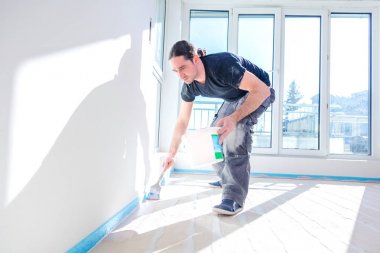 Beton zemine makaralı astar koyan işçi. Yapım aşamasında olan ev.