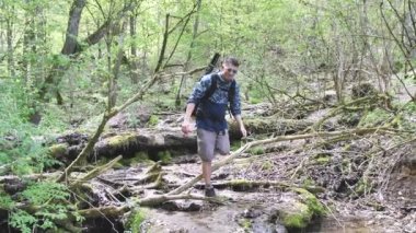 Sırt çantalı genç adam ormanda yürüyüş yapıyor.