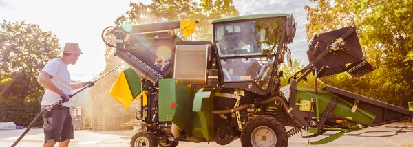 農場の庭で黄色と緑のコンバイン ハーベスターを修理する整備士 — ストック写真