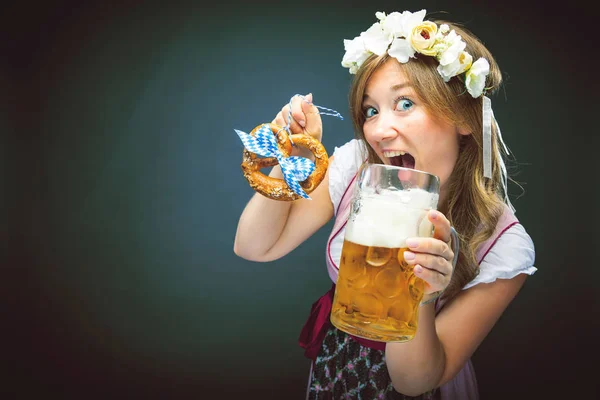 伝統的なバイエルンのダーンドルで美しい女性は カメラを見て ビールグラスとプレッツェルを保持 — ストック写真
