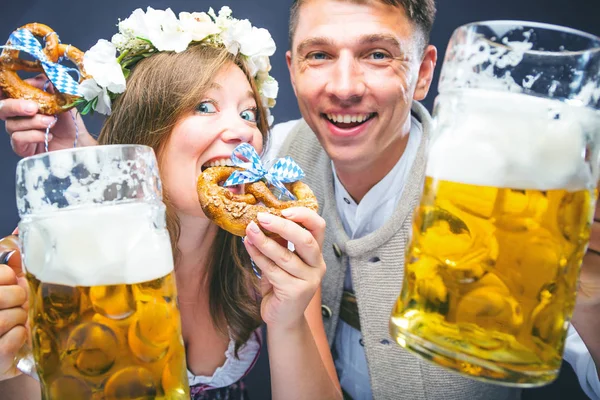 ビールとプレッツェルのグラスを持つ幸せな若い男女 オクトーバーフェストコンセプト — ストック写真
