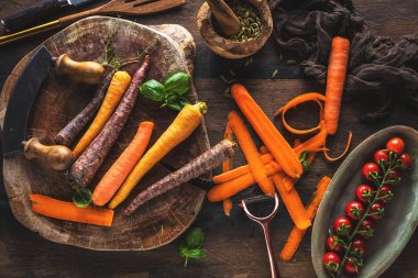 ahşap masada taze çiğ gökkuşağı havuç ve domates üst görünümü