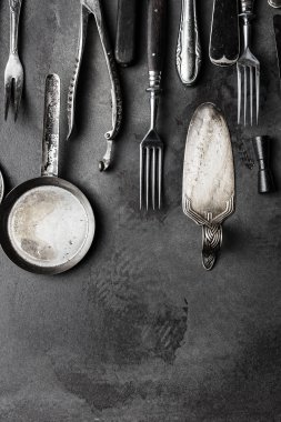 Koyu desenli arka planda eski çatal bıçak takımı, üst görünüm