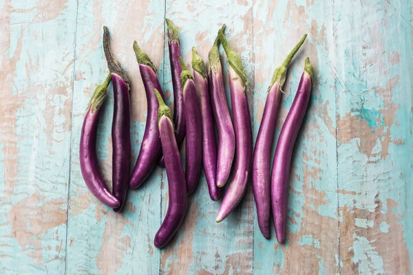 top view of fresh purple japanese eggplants on rustic colored wooden background