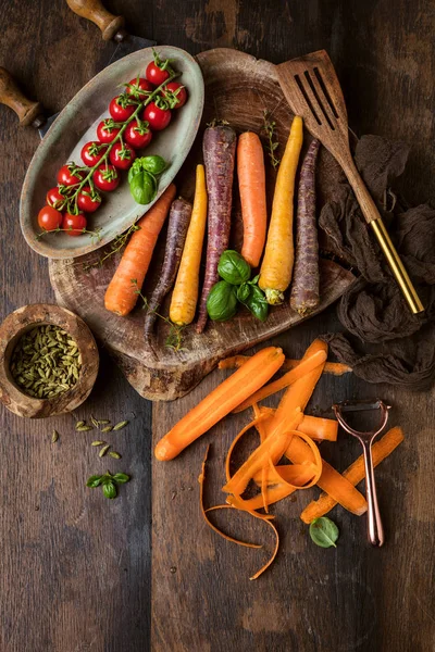 fresh organic rainbow carrots and tomatoes on wooden table