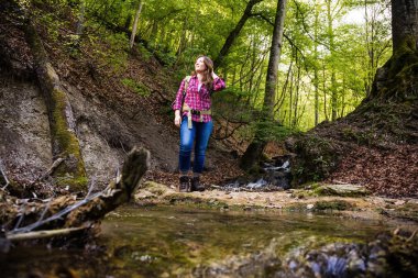 güzel ormanda sırt çantası ile güzel kız bir şelale yakın yürüyüş yaparken 