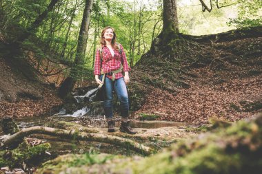 güzel ormanda sırt çantası ile güzel kız bir şelale yakın yürüyüş yaparken 