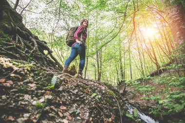 güzel ormanda sırt çantası ile gülümseyen genç kadının düşük açı görünümü  