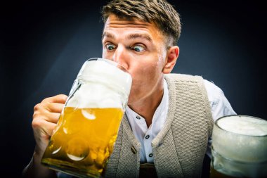 Genç adam bira gözlük ve gri arka planda izole bira içme