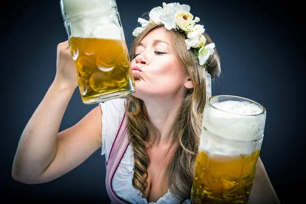 excited young woman holding beer glasses isolated on grey background
